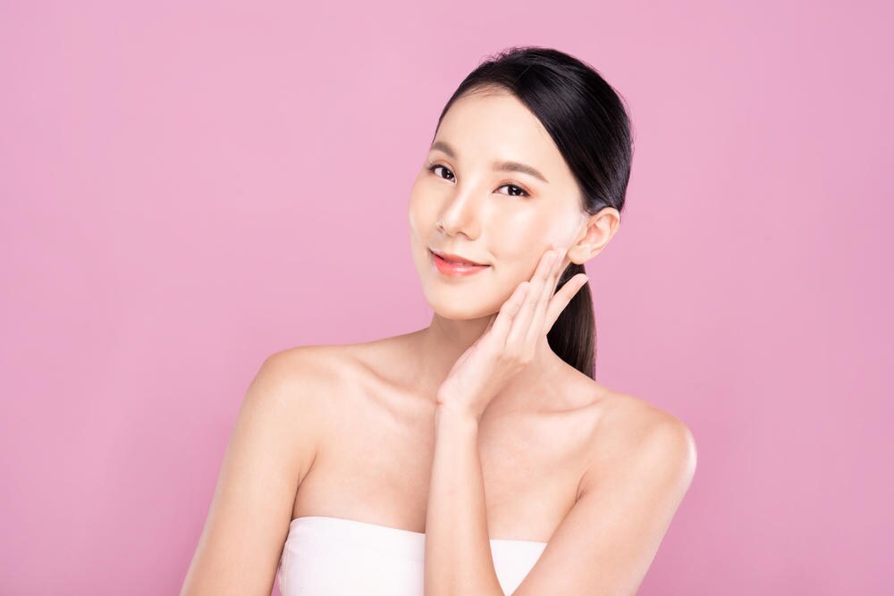 Perempuan memegang pipi dengan backgrond pink
